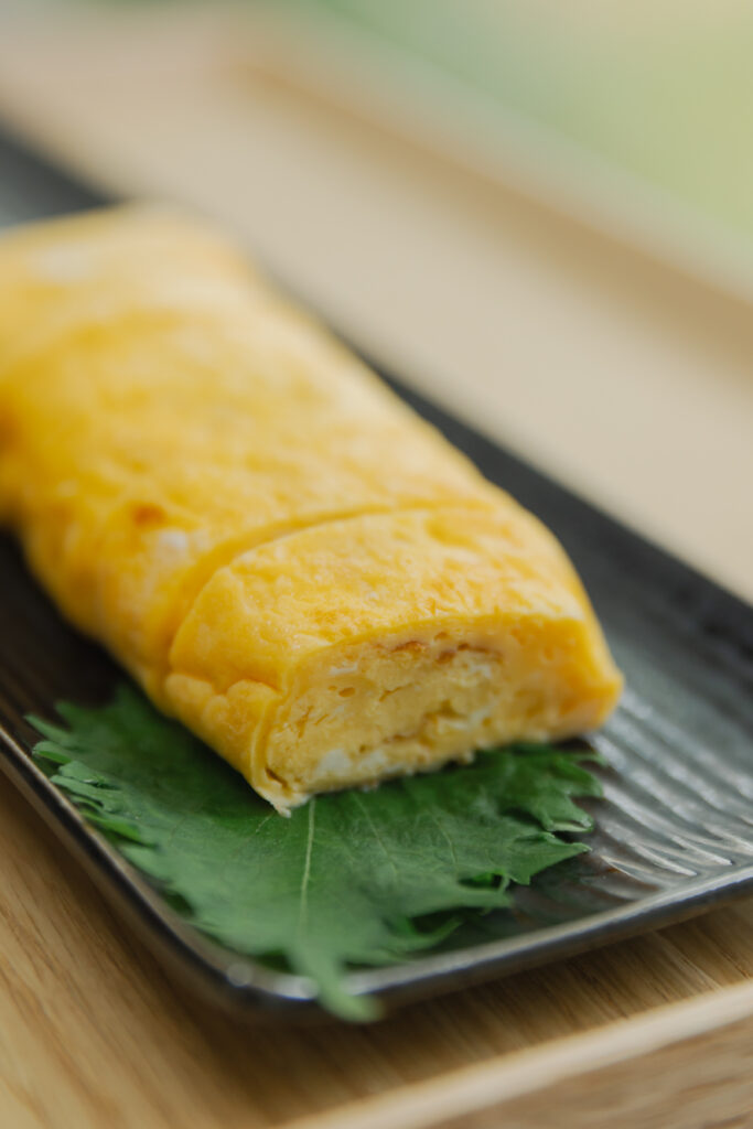 Homemade sweet and savory Japanese tamagoyaki rolled omelet sliced on a plate