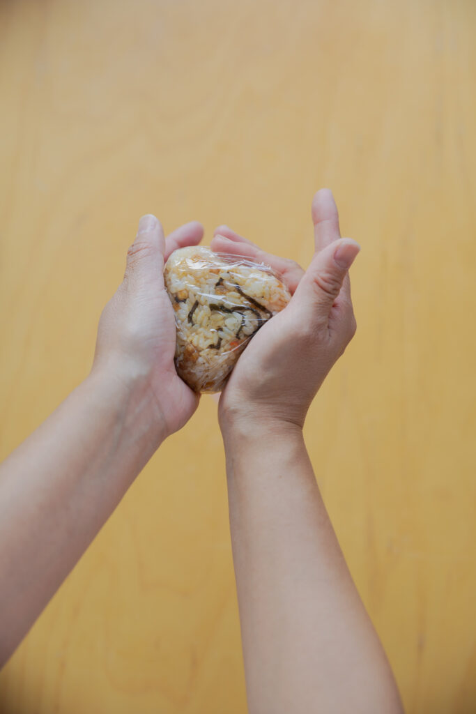 Four types of Japanese onigiri rice balls including salmon and tuna mayo on a bamboo basket