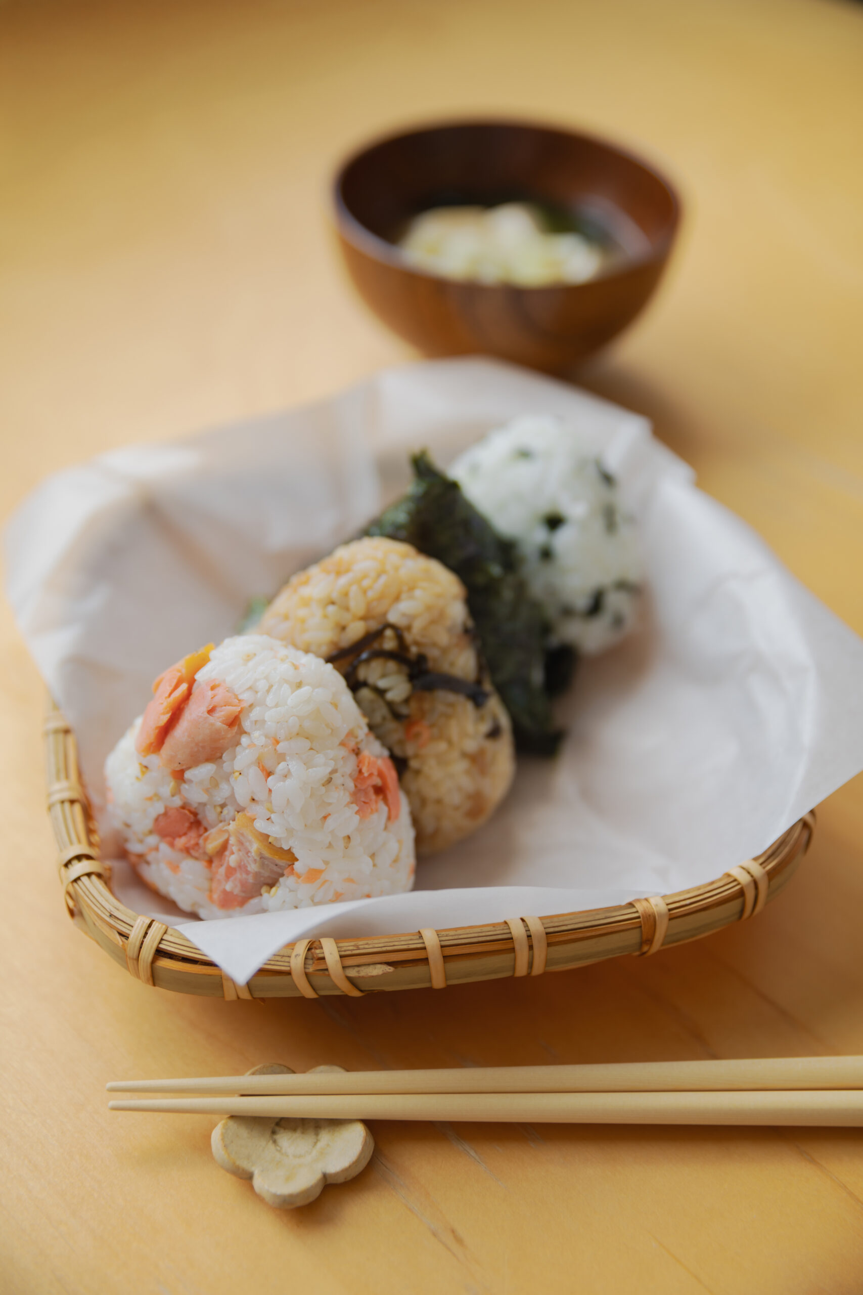Four types of Japanese onigiri rice balls including salmon and tuna mayo on a bamboo basket