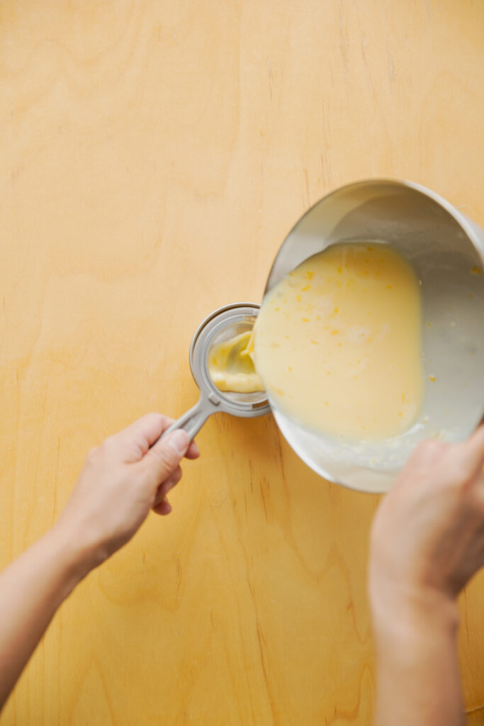 Straining the custard pudding liquid through a fine mesh sieve into a cup