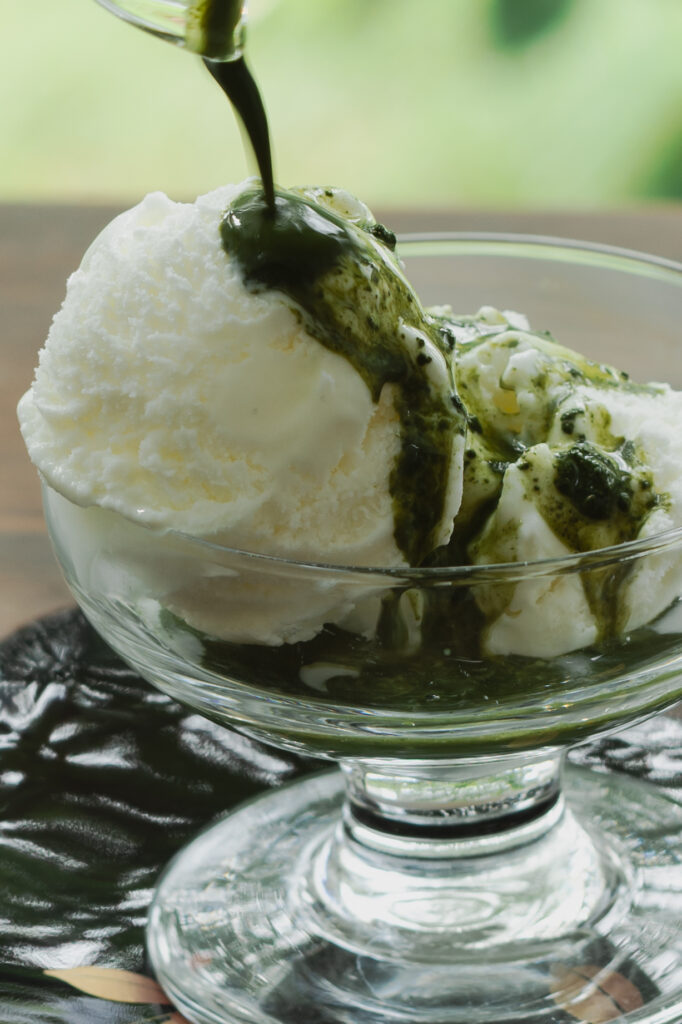 Cafe-style Japanese matcha affogato dessert with rich green matcha poured over vanilla ice cream in a glass bowl