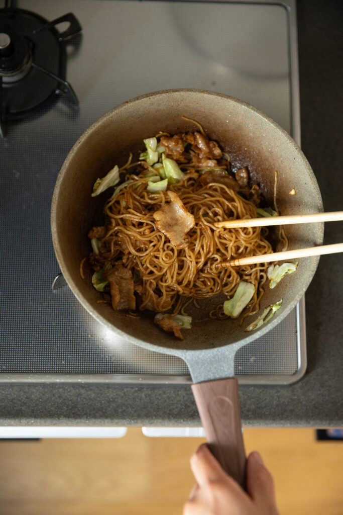 Tossing yakisoba noodles with rich brown savory sauce in a hot skillet