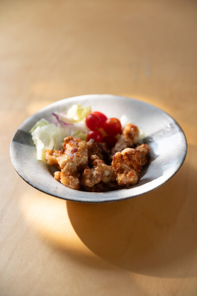 Crispy golden Japanese Karaage fried chicken served in a ceramic bowl with cherry tomatoes
