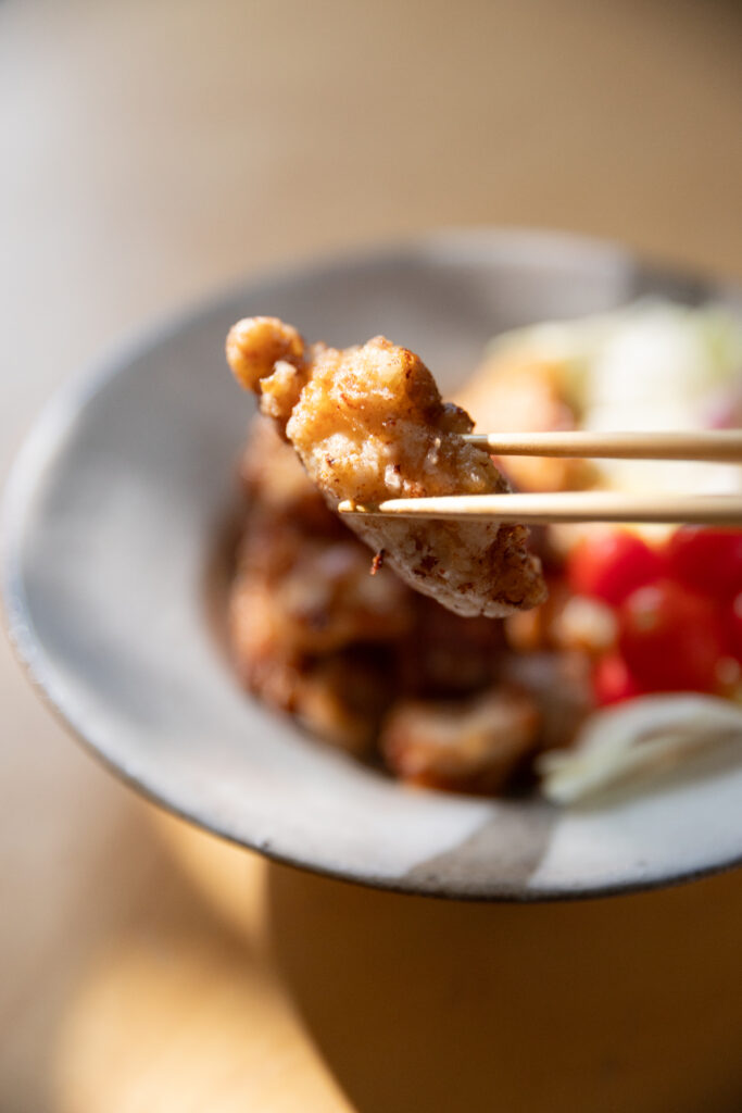 Crispy golden Japanese Karaage fried chicken served in a ceramic bowl with cherry tomatoes