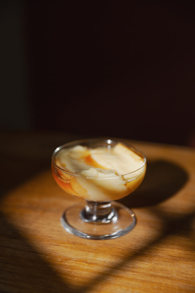 Silky and ultra-soft authentic Japanese steamed custard pudding with glossy caramel sauce in a glass cup under beautiful spotlight