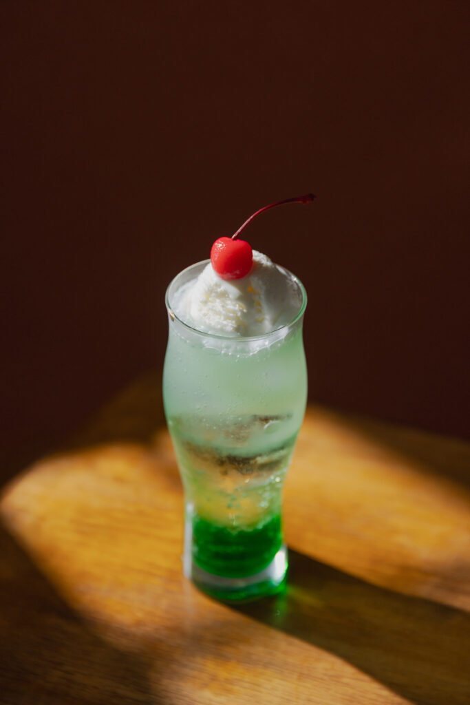Dramatic spotlight casting beautiful shadows behind a sparkling green Japanese melon cream soda