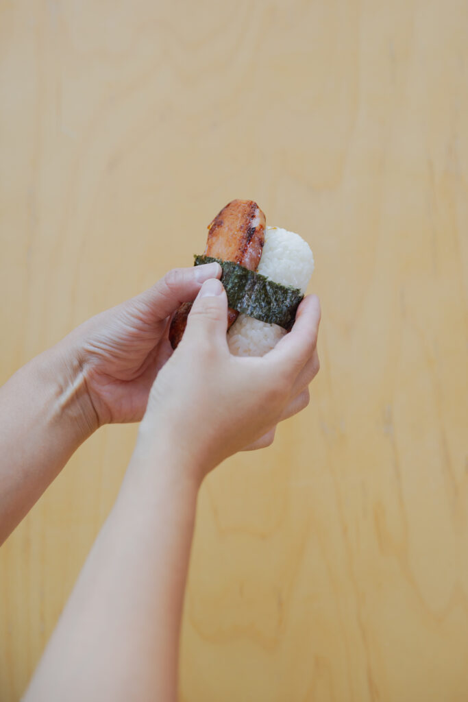 Wrapping a crispy seaweed nori band around a glazed Spam musubi rice ball