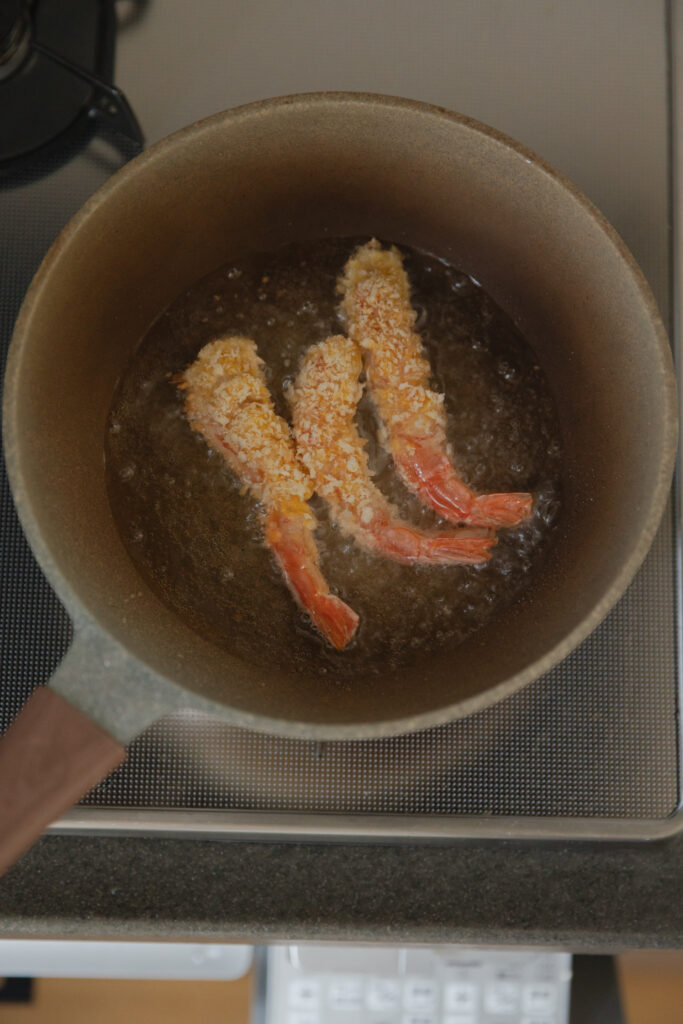 Deep-frying crispy Japanese Ebi Fry shrimp in a pot of hot boiling oil on a stove